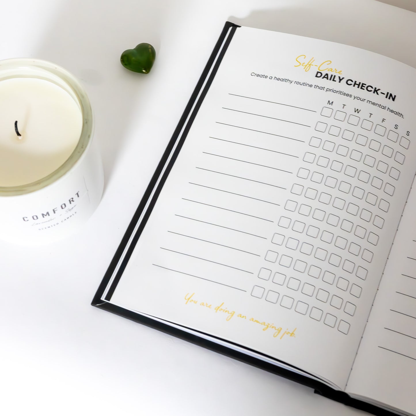 Filmmaking planner, open on the self-care daily check-in page, next to a candle for aesthetic purposes on a white background