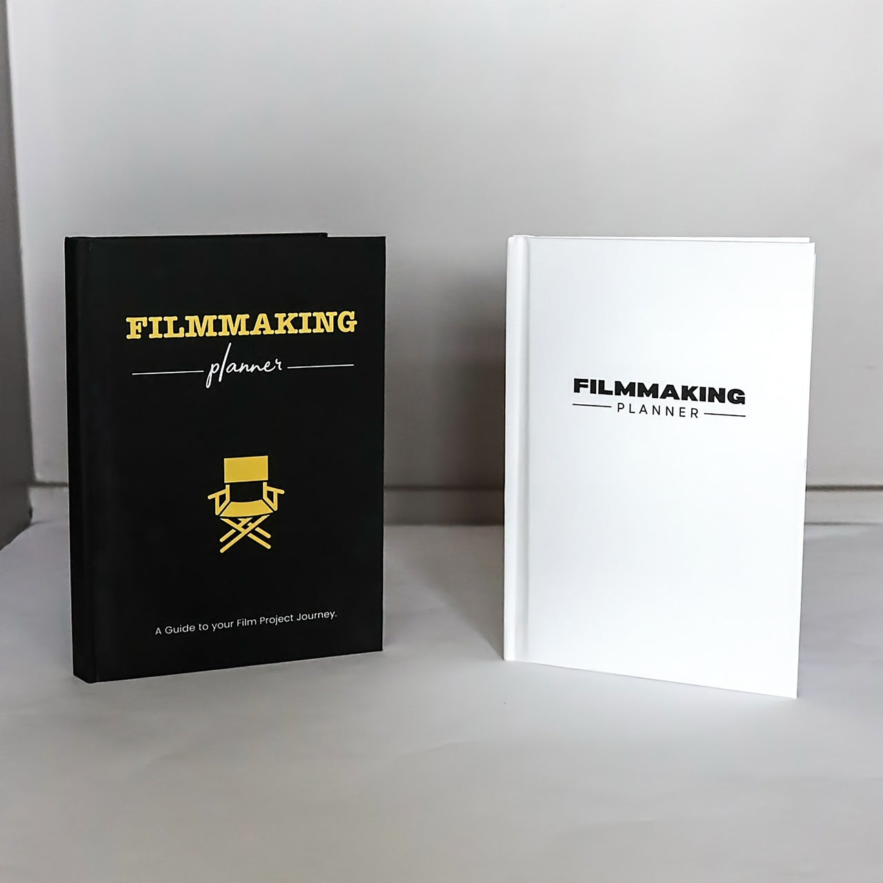 Two A5, Hardback Books, Black and Yellow Filmmaking Planner and White with black font The Ultimate Film Production Planner product photography 