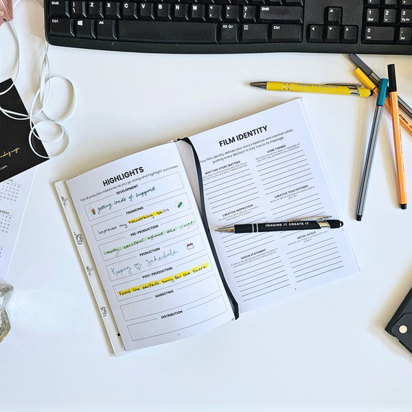 Notebook with film identity planning on a desk with pens and a keyboard.
