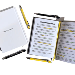 Notebook with open pages displaying 'Filmmaking Terms' and surrounded by pens on a white background.
