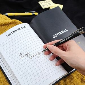 Meeting notes with lined paper and a hand holding a pen saying never give up.  