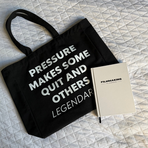 Black tote bag with motivational quote and beige notebook on a textured surface