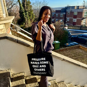 Woman holding a black bag with text, standing on steps outdoors.