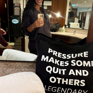 Person holding a black bag with text in a bathroom setting