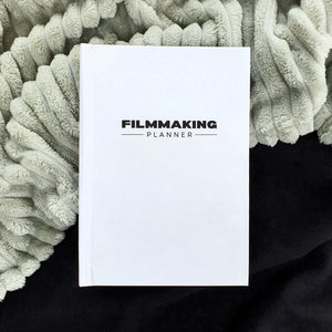 While, A5 filmmaking planner against grey and black material 